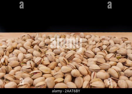 Guscio pistacchi sul tavolo di legno e sfondo nero. Pistacchi concetto con copyspace. Foto Stock