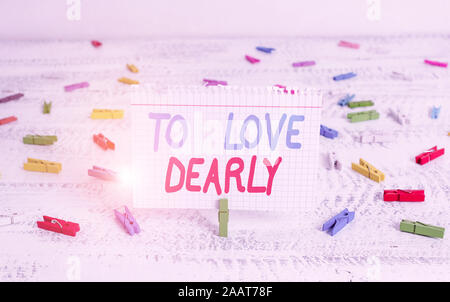 La grafia la scrittura di testo per amare teneramente. Foto concettuale amare qualcuno molto più in modo umile e smarrendosi clothespin verde legno bianco indietro Foto Stock