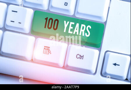 La scrittura della nota mostra 100 anni. Il concetto di business per ricordare un giorno speciale per essendo 100 anni di esistenza White tastiera PC con nota sopra carta Foto Stock