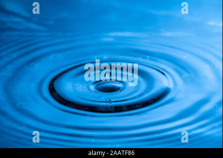 Alta velocità di caduta di acqua fotografia. Blu con una sola goccia circa a splash Foto Stock