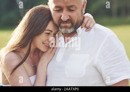 Bel uomo vecchio e giovane e bella ragazza sono abbracciava, figlia e suo vecchio papà trascorrere del tempo insieme all'aperto Foto Stock