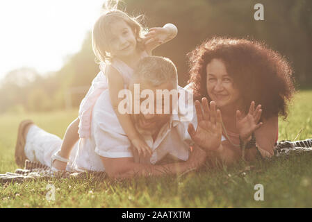 Un simpatico bambina è di trascorrere del tempo con il suo amato nonno e grandmather nel parco. Essi avevano un picnic sull'erba Foto Stock