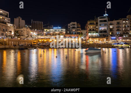 Paceville distretto a notte in St Julian città in Malta, popolare vita notturna hotspot, vista da Spinola Bay Foto Stock