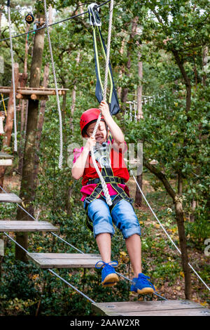 Ragazza di un alto corso di corda in foresta Foto Stock