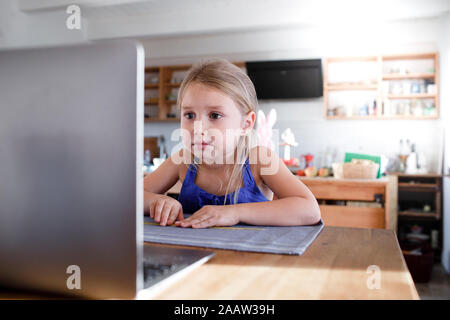 Ritratto di bambina in cucina a casa staring al laptop Foto Stock