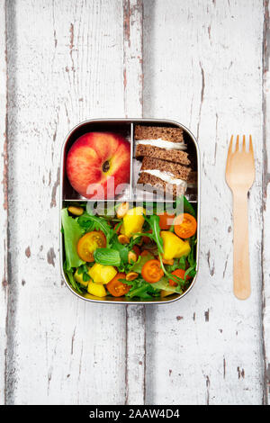 Close-up di lunchbox con mango insalata, pane di segale panino e pesca Foto Stock