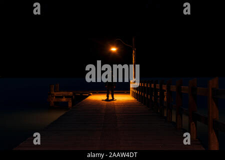 Vista posteriore di un uomo in piedi sul molo di notte Foto Stock