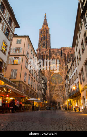 Strada in mezzo edifici contro Notre Dame de Strasbourg al tramonto, Francia Foto Stock