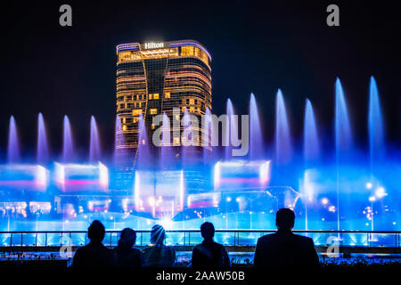 Tashkent, Uzbekistan - 30 Ottobre, 2019: guardare la gente ballare fontana illuminata di notte nella nuova città di Tashkent Park Foto Stock