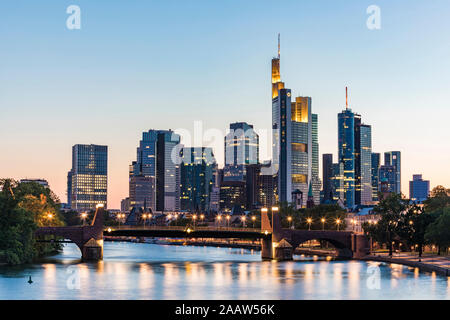 Illuminata ponte sul fiume contro il cielo chiaro durante il tramonto a Francoforte, Germania Foto Stock