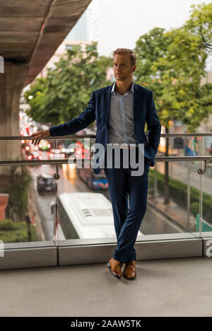 Giovane imprenditore sul ponte pedonale, guardando dal lato Foto Stock