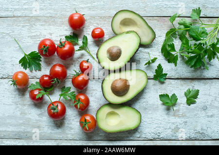 Direttamente sopra il colpo di avocado con pomodori e prezzemolo sul tavolo di legno Foto Stock