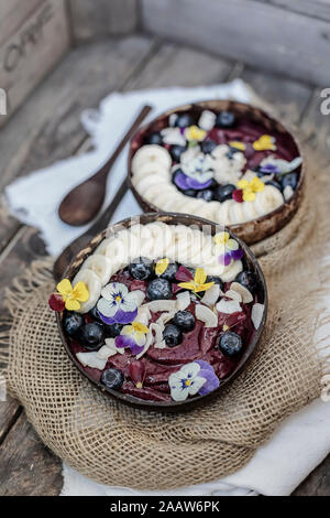 Angolo di alta vista di gelato guarnita con frutta e fiori servita in ciotole sul tavolo Foto Stock