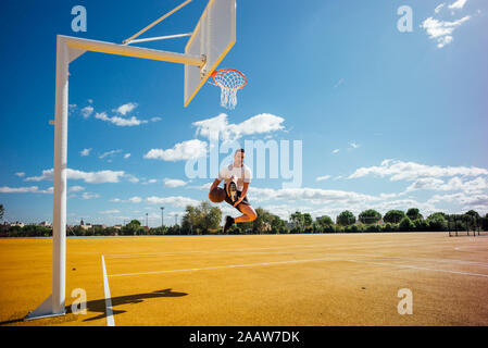 L'uomo giocare a basket sulla corte giallo, dunking Foto Stock