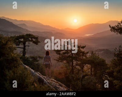 Escursionista femmina in piedi sul punto di vista, Albertacce, Lac de Calacuccia presso sunrise, Haute-Corse, Corsica, Francia Foto Stock