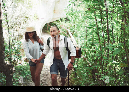 Due escursionisti con zaini sulla schiena in natura. L uomo e la donna si tengono per mano mentre cammina su un giorno di estate Foto Stock