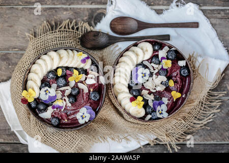 Direttamente sopra il colpo di gelato guarnita con frutta e fiori servita in ciotole sul tavolo Foto Stock