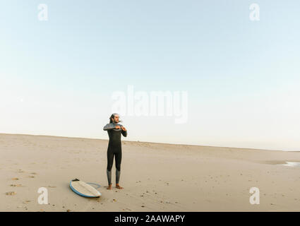 Il Portogallo, Costa Nova, Surfer messo su neoprene in piedi presso la spiaggia Foto Stock