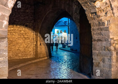 Ingresso ad arco con muri in pietra e la vecchia città di Ioannina di notte, Grecia Foto Stock