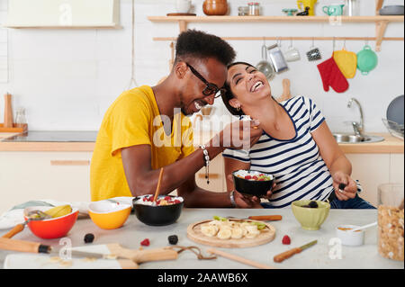 Multietnica giovane ridendo, breakfasting insieme in cucina Foto Stock