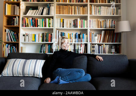 Felice donna matura rilassante sul lettino a casa Foto Stock