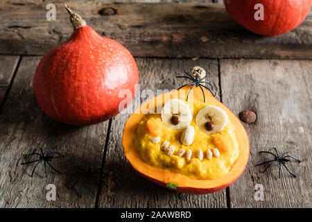 Angolo di alta vista di zucca con faccia antropomorfo su un tavolo di legno durante il periodo di Halloween Foto Stock