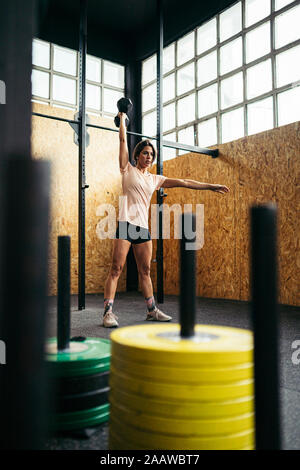 Giovane donna facendo dumbbell esercizio in palestra Foto Stock