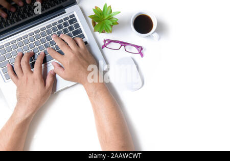 Ufficio bianco scrittoio con man mano tpying qualcosa sul laptop. Vista superiore, piatto laici. Foto Stock