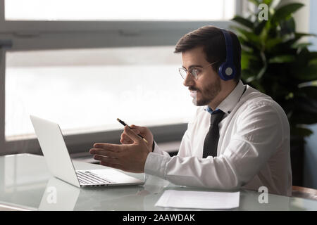 Grave giovane imprenditore nelle cuffie talk online Foto Stock