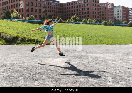 Giovane donna di salto e in esecuzione nella città in estate Foto Stock