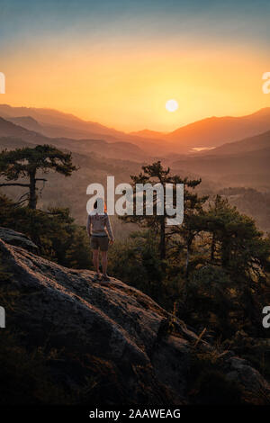 Escursionista femmina in piedi sul punto di vista, Albertacce, Lac de Calacuccia presso sunrise, Haute-Corse, Corsica, Francia Foto Stock