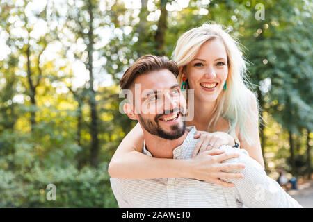 Ritratto di felice giovane uomo dando la sua ragazza un piggyback ride Foto Stock
