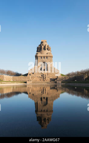 Il lago di lacrime con la riflessione del Völkerschlachtdenkmal contro il cielo blu chiaro, in Sassonia, Germania Foto Stock