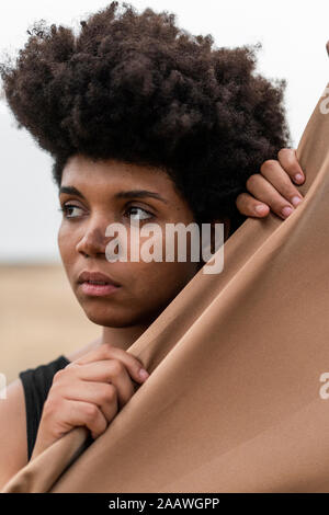Ritratto di giovane donna dietro il panno guardando a distanza Foto Stock