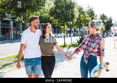 Tre amici passeggiando insieme divertendosi Foto Stock