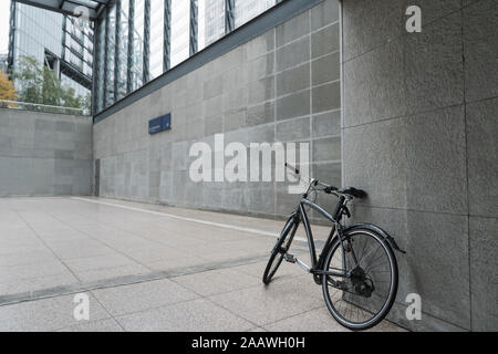 Bicicletta nero appoggiata contro la parete di edificio della stazione a Potsdamer Platz, Berlin, Germania Foto Stock