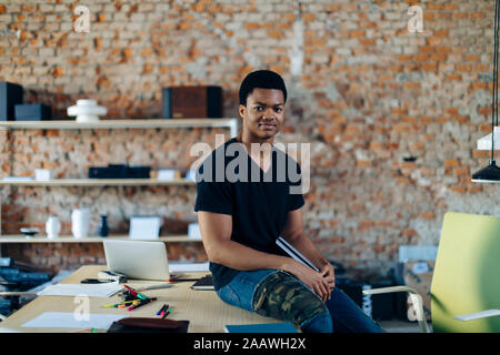 Ritratto di fiducioso giovane alla tabella in ufficio Foto Stock