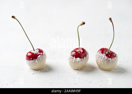 Close-up di ciliegie ricoperto di cioccolato bianco e cocco grattugiato Foto Stock