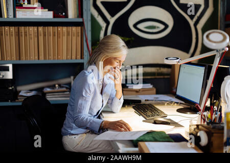 Donna matura lavorando in architct dell'ufficio, controllo planimetrie Foto Stock