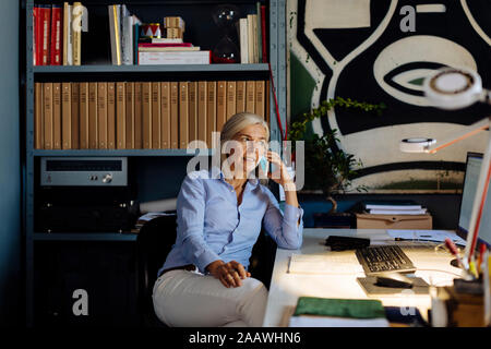 Donna matura lavorando in architct di ufficio, parlando al telefono Foto Stock