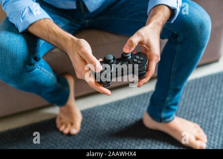 Le mani di uomo a piedi nudi la riproduzione di giochi per computer a casa, close-up Foto Stock