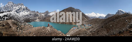 Donna seduta su roccia al lago di Gokyo, Solo Khumbu, in Nepal Foto Stock