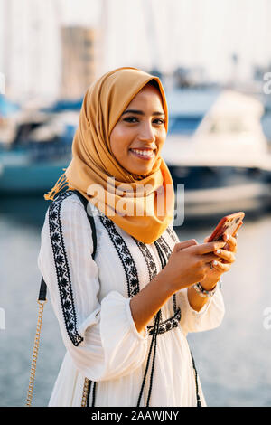 Giovane donna musulmana che indossa il hijab giallo a piedi il porto Foto Stock