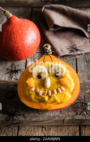 Angolo di alta vista di zucca con faccia antropomorfa sul tavolo durante il periodo di Halloween Foto Stock