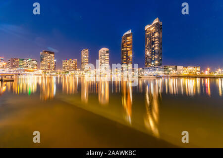 Edifici illuminati dal Fiume Yarra a Docklands contro sky, Melbourne, Australia Foto Stock