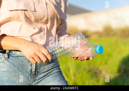 Donna di mani tenendo le bottiglie di plastica vuote, close-up Foto Stock