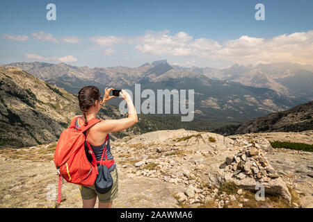 Escursionista femmina durante l'escursione, fotografare con il suo punto di vista, Haute-Corse, Corsica, Francia Foto Stock