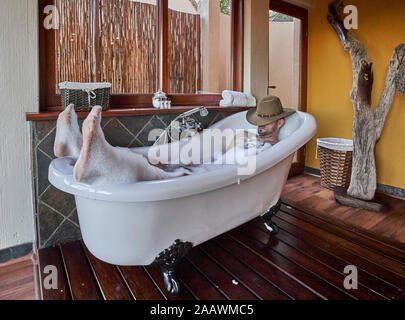 L'uomo avente un bagno rilassante nella vasca da bagno Foto Stock