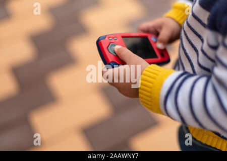 Le mani del ragazzino azienda giocattolo mobile phone, close-up Foto Stock