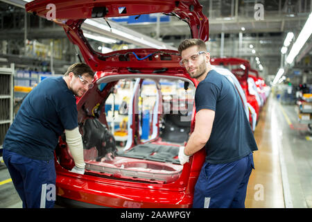 Due colleghi impegnati nella moderna fabbrica di automobili Foto Stock